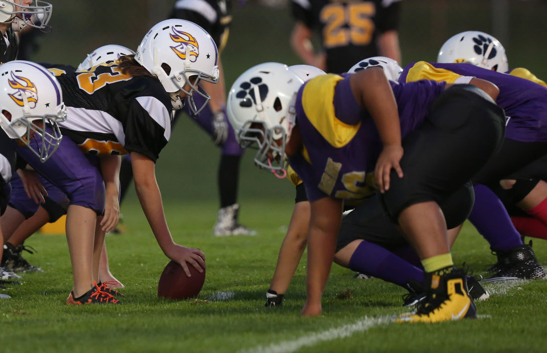 Youth football players line up at the line of scrimmage. Photo by Michelle Stocker for the Cap Times.